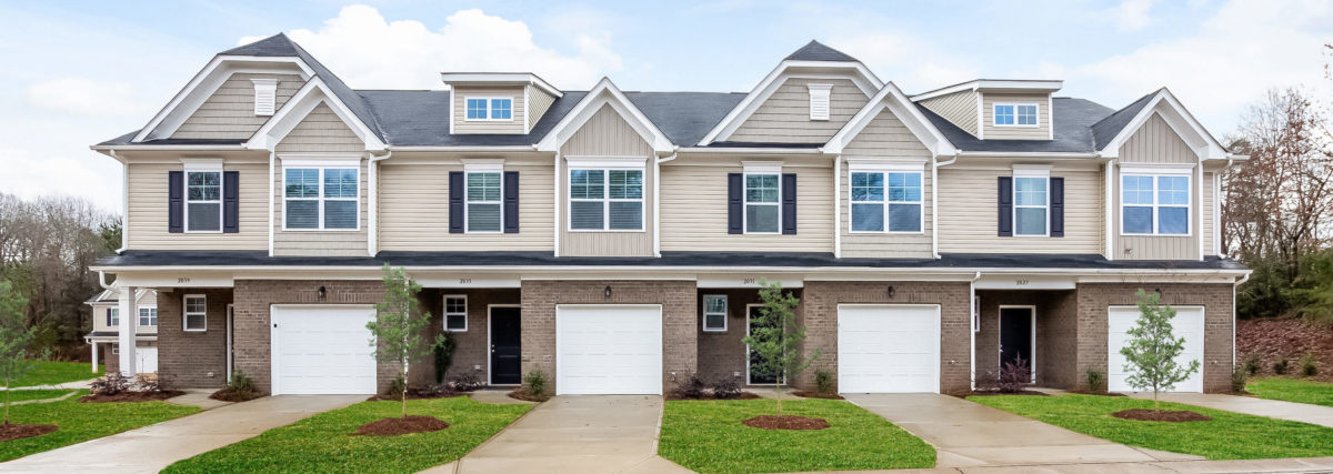 Row of two-story, beige and brick colored townhomes with white trim.