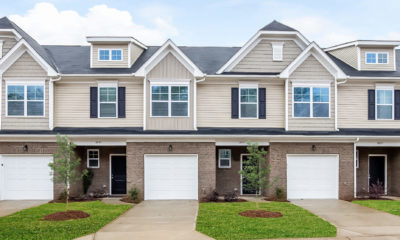 Row of two-story, beige and brick colored townhomes with white trim.