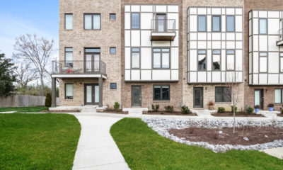 Front view of three-story, brick townhomes with landscaped front yard.