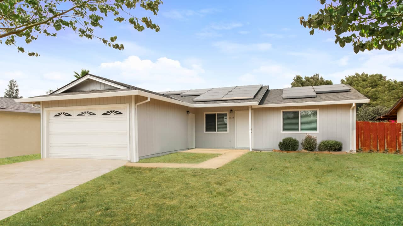 Front view of light grey house and with white trim and solar panels on roof