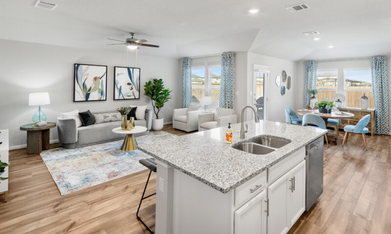 View of kitchen island with furnished living room and dining room in foreground.