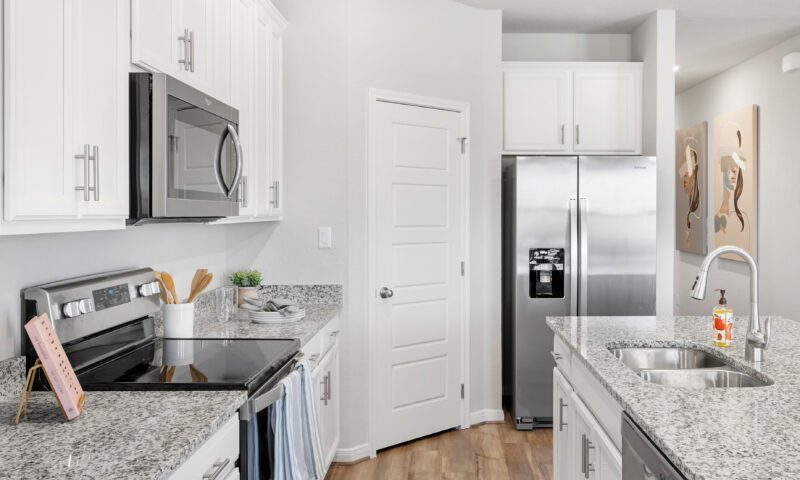 View of kitchen with close-up view of stainless steel appliances such as fridge, microwave, and stove.