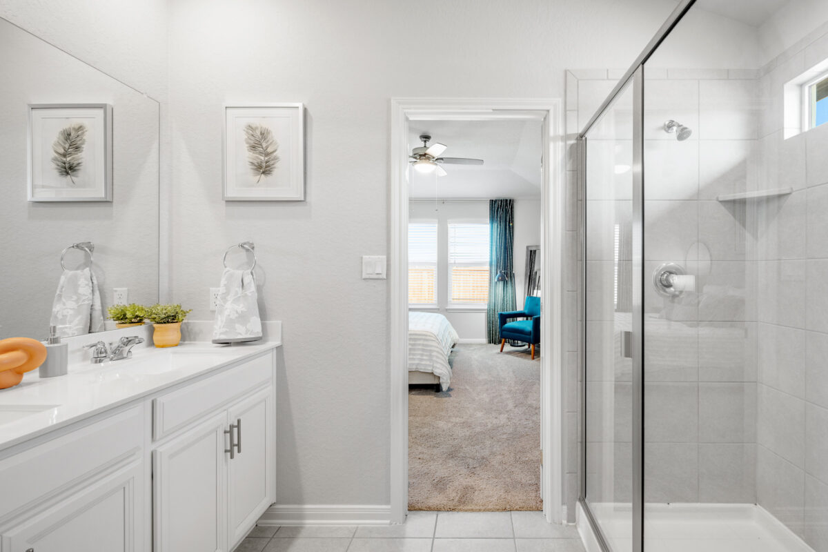 Close-up view of primary shower, countertop and view into main bedroom.