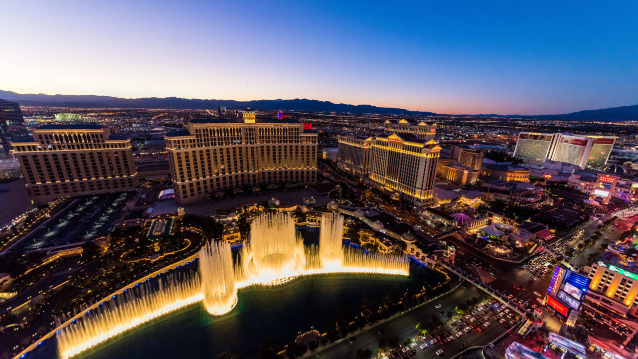 Night time high-angle view of hotels and casinos with focus on large water fountain.