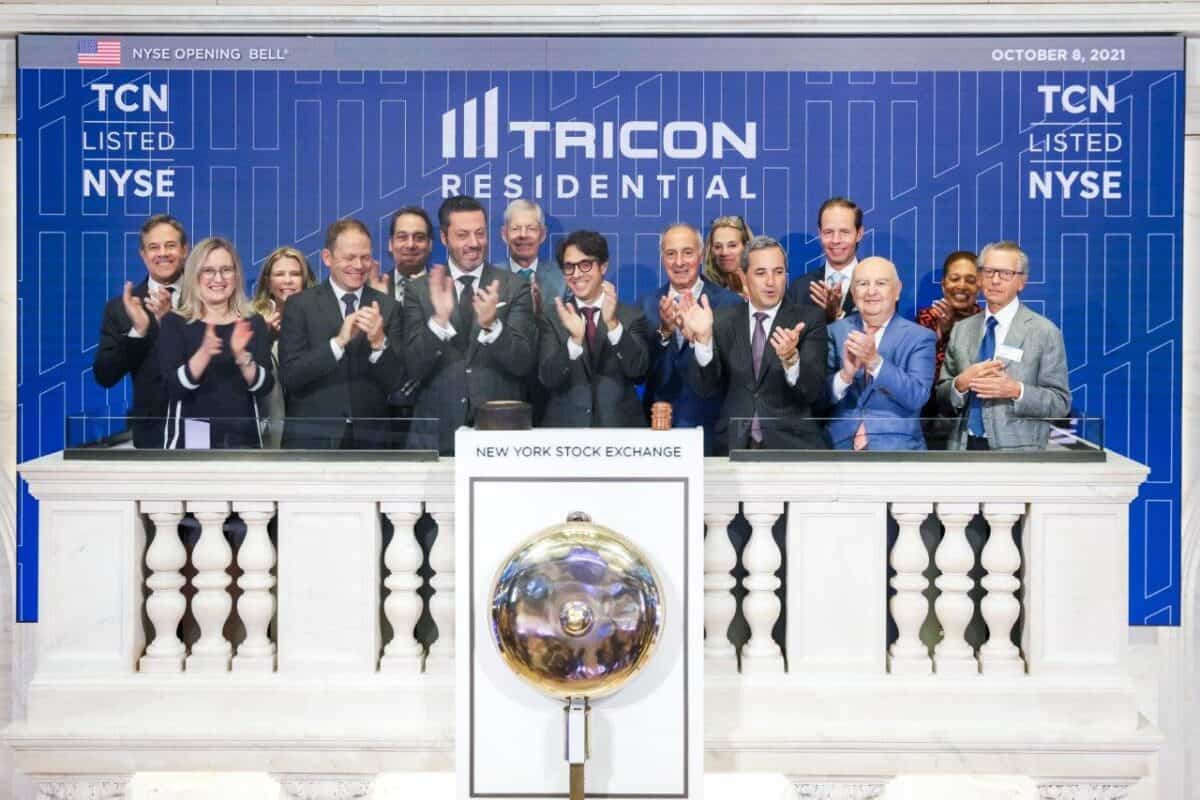 A group business people clapping in front of New York Stock Exchange bell.