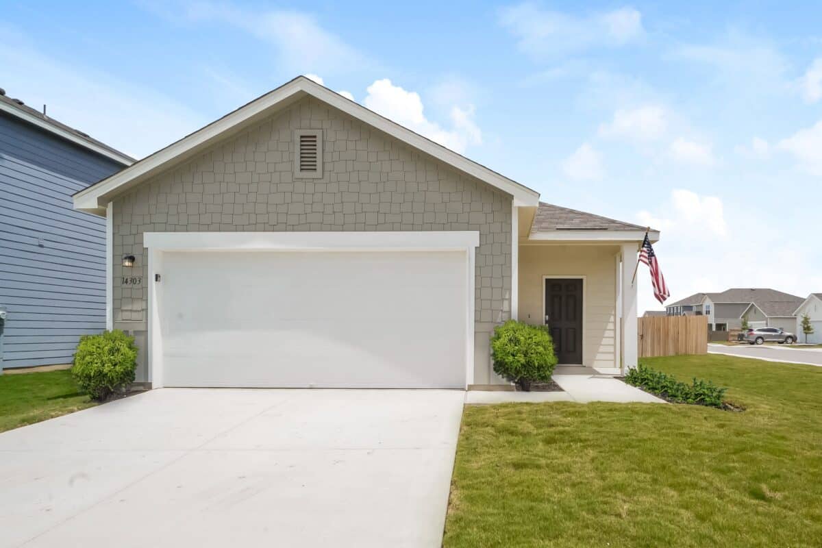 Exterior view of grey and beige house with white trim and dark brown door.