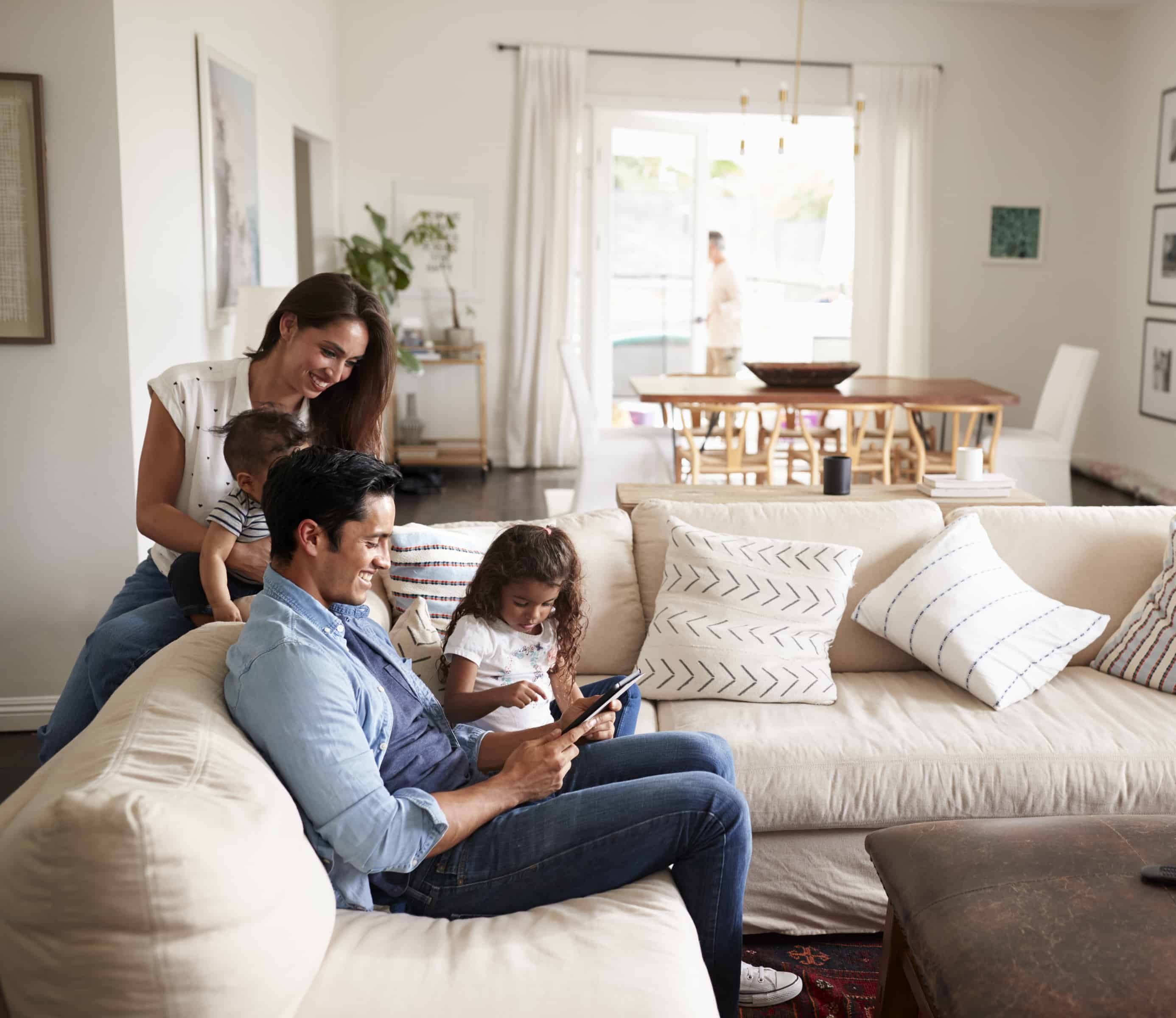 Young Hispanic family sitting on sofa reading a book together in their living room