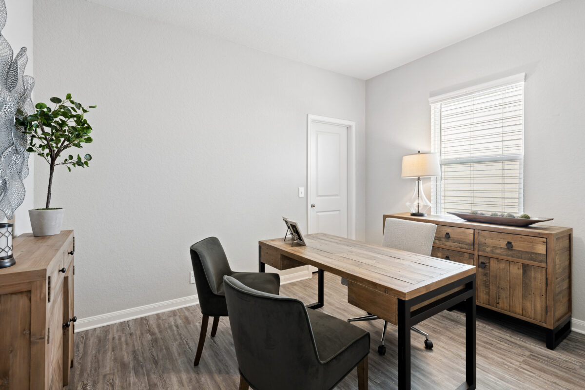 View of staged office with desk and chairs, and two-inch window blinds.