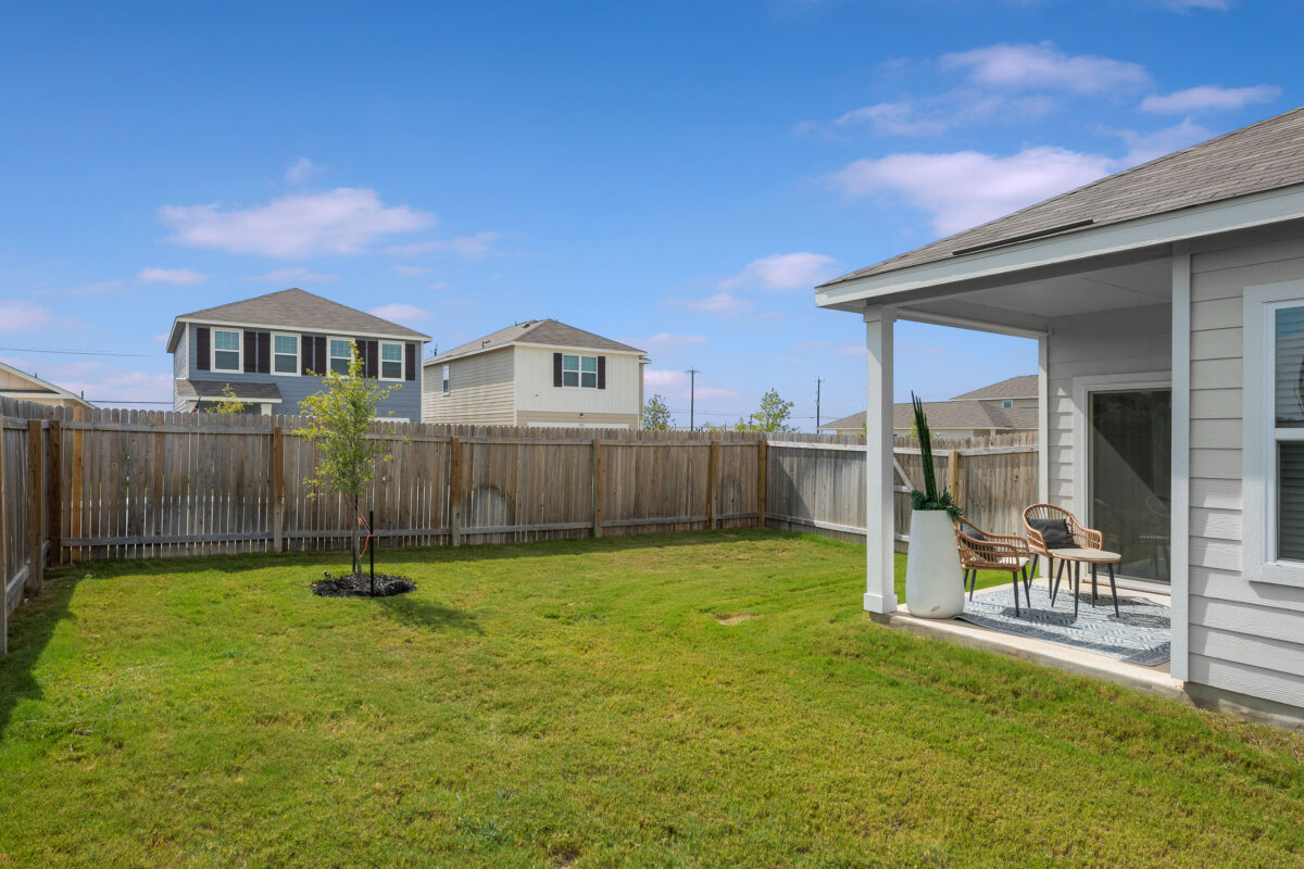 View of home with fully fenced backyard, patio seating for two in the Trails at Culebra community.