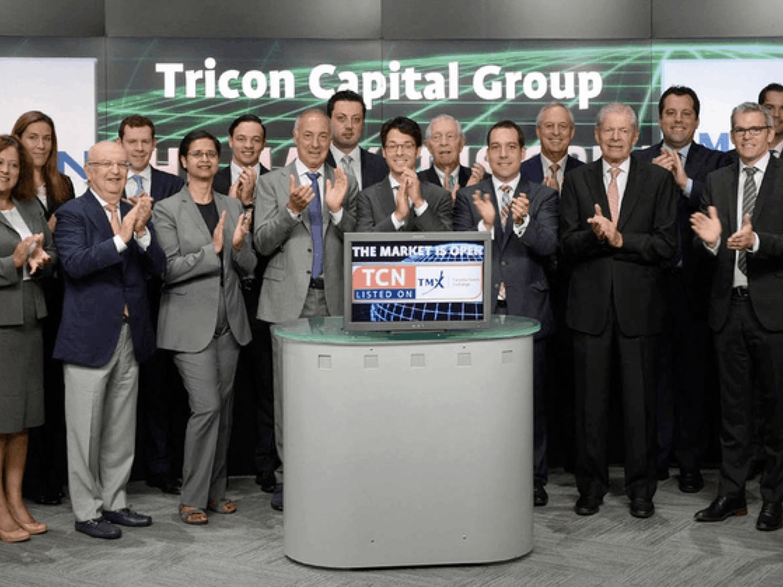 A group of business people standing in front of podium clapping.