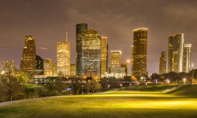 Night time shot of green space in forefront and city skyline with high-rise buildings in the background.
