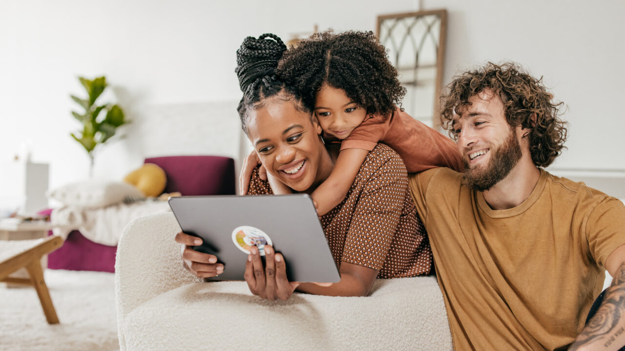 Smiling parents and daughter at home watching online movie together