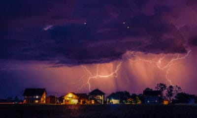 Lighting storm hovers above a group of homes.