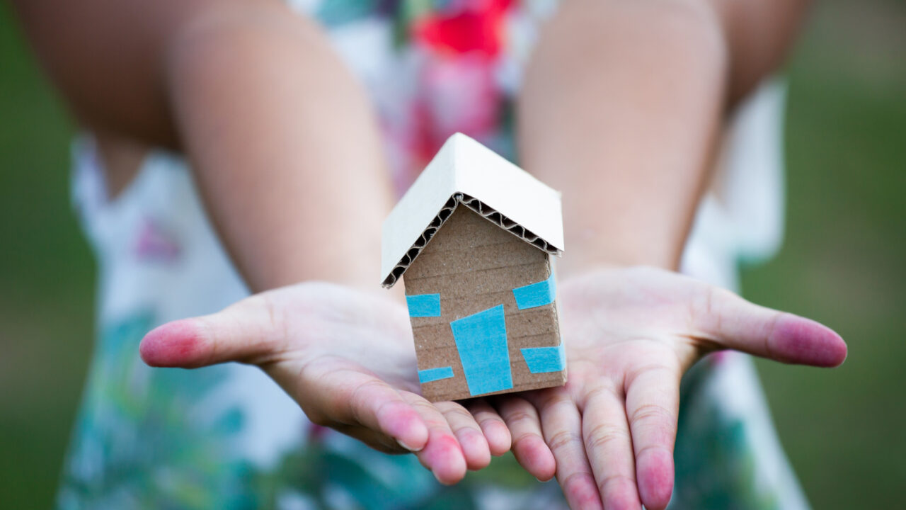 Child holding paper house in hands as real estate and family home concept stock photo